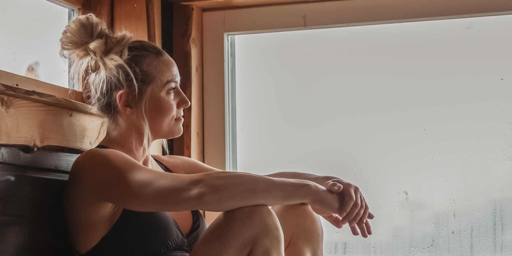 Woman sitting in sauna room enjoying the steam of sauna heater